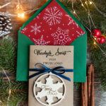 Kartki świąteczne dla firm: Drewniana bombka z logo jako zawieszka na choinkę i świąteczna kartka firmowa z motywem śnieżynki